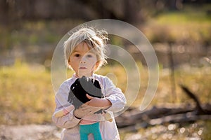 Little toddler blond child, boy, playing with handknitted doll