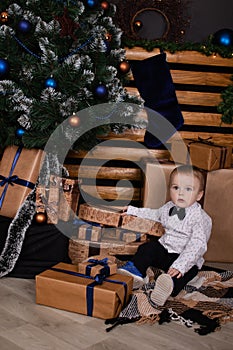 little toddler blonde boy near christmas tree in dark loft room with blue decoration. happy new year