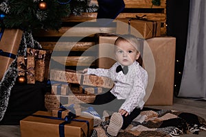 little toddler blonde boy near christmas tree in dark loft room with blue decoration. happy new year