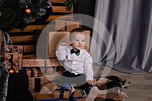 little toddler blonde boy near christmas tree in dark loft room with blue decoration. happy new year