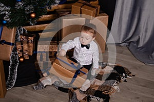 little toddler blonde boy near christmas tree in dark loft room with blue decoration. happy new year