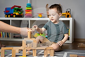 Little toddler boy 2.5 years playing wooden blocks with dad. Spending time with children. Educational activities for kids.