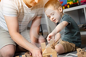 Little toddler boy 2.5 years playing wooden blocks with dad. Spending time with children. Educational activities for kids.