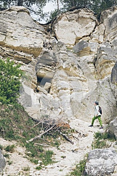 little toddler boy with backpack climbing by rock