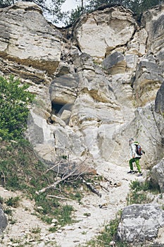 little toddler boy with backpack climbing by rock