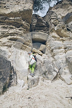 little toddler boy with backpack climbing by rock