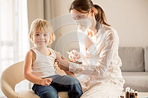 Little toddler boy, getting injection in consulting room from pediatrition