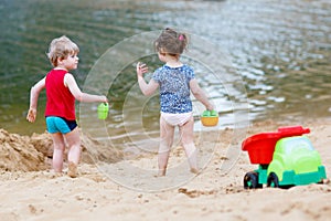 Little toddler boy and girl playing together with sand toys near