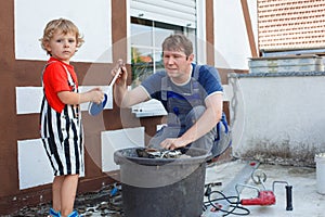 Little toddler boy helping his father with renovation of home