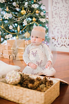 Little toddler boy at home at the Christmas tree with gifts and toys.