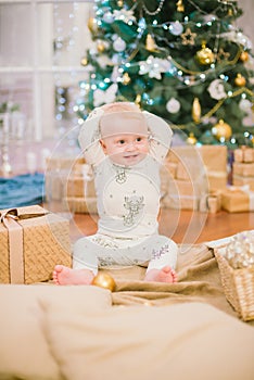 Little toddler boy at home at the Christmas tree with gifts and toys.