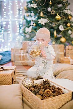 Little toddler boy at home at the Christmas tree with gifts and toys.