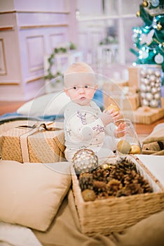 Little toddler boy at home at the Christmas tree with gifts and toys.