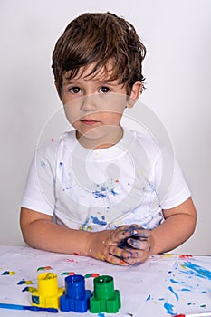 Little toddler boy kid with dirty face and dirty clothes painting at home.