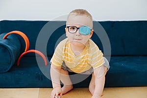 Little toddler boy in lazy eye patch is playing with toy cars photo