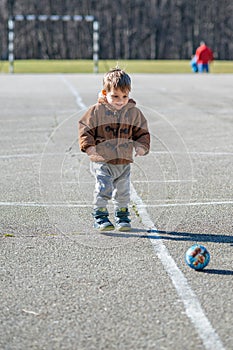 Little toddler boy, playing with ball on playground