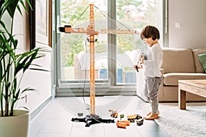 Little toddler boy playing with big construction building crane toy at home