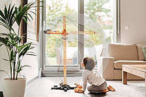 Little toddler boy playing with big construction building crane toy at home