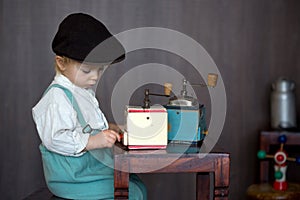 Little toddler boy, playing with mill at home, sitting on vintage table