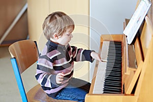 Little toddler boy playing piano at music school.