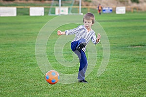 Little toddler boy playing soccer and football, having fun outdo
