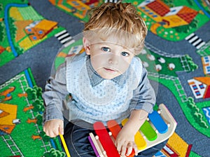 Little toddler boy playing with wooden music toy