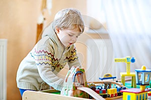 Little toddler boy playing with wooden railway, indoors