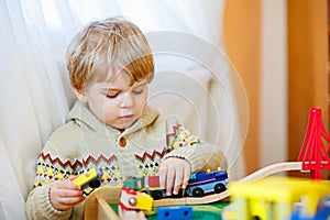 Little toddler boy playing with wooden railway, indoors