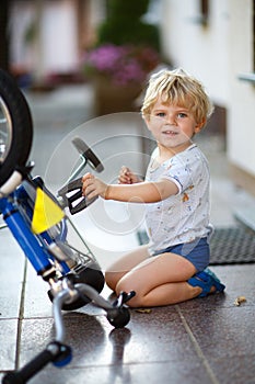 Little toddler boy repairing his first bike