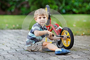 Little toddler boy repairing his first bike