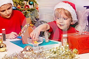 Little toddler boy takes candy to put on the gingerbread house