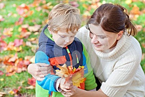 Little toddler boy and young mother in the autumn park