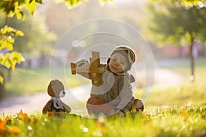 Little toddler child, boy, playing with airplane and knitted teddy bear in autumn park