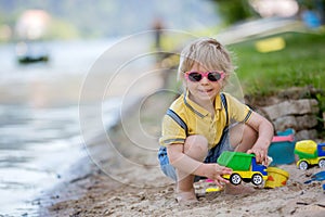 Little toddler child, cute boy, playing with toys in the sand on a lake