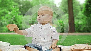 Little toddler eating bread at picnic. Cute children spending time in park