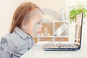 Little toddler girl amazed at something she see on her laptop