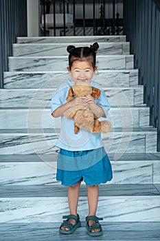 Little toddler girl in blue t-shirt holds brown dog toy