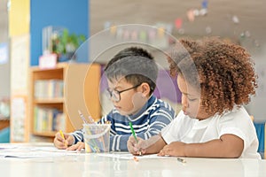 Little toddler girl and boy concentrate  drawing together.  Asian boy and Mix African girl learn and play together in the pre-
