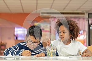 Little toddler girl and boy drawing together.  Asian boy and Mix African girl learn and play together in the pre-school class.