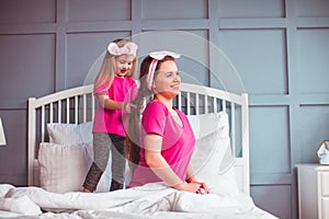 Little toddler girl combing her mother hair