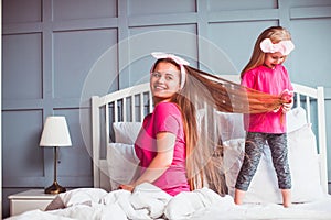 Little toddler girl combing her mother hair