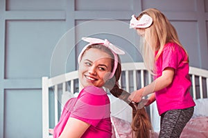 Little toddler girl combing her mother hair