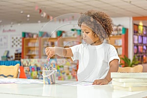 Little toddler girl concentrate on drawing. Mix African girl learn and play in the pre-school class. Children enjoy hand writing photo