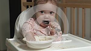 Little toddler girl eating porridge.