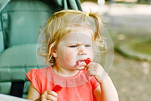 Little toddler girl eating red pepper and vegetables for healthy lunch snack sitting in baby stroller. happy child and