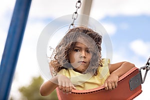 Little toddler girl having fun on swing at playground in the summer, childhood memories and kids activity concept