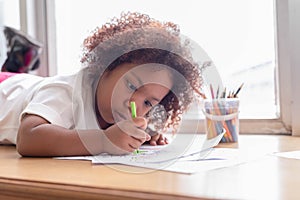 Little toddler girl laying down concentrate on drawing. Mix African girl learn and play in the pre-school class. Children enjoy