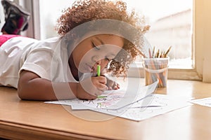 Little toddler girl laying down concentrate on drawing.  Mix African girl learn and play in the pre-school class. Children enjoy