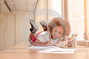 Little toddler girl laying down concentrate on drawing.  Mix African girl learn and play in the pre-school class. Children enjoy