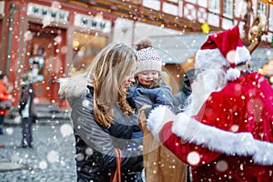 Little toddler girl with mother on Christmas market.